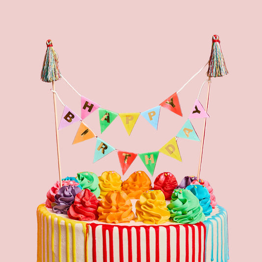 Colorful birthday cake with rainbow frosting and a 'Happy Birthday' banner on a white background
