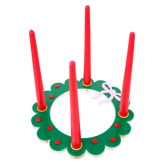 Christmas-themed advent candle with red candles and green base on a white background