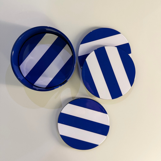 four round coasters with a blue and white striped pattern, including one open round container, displayed on a light cream-colored surface.
