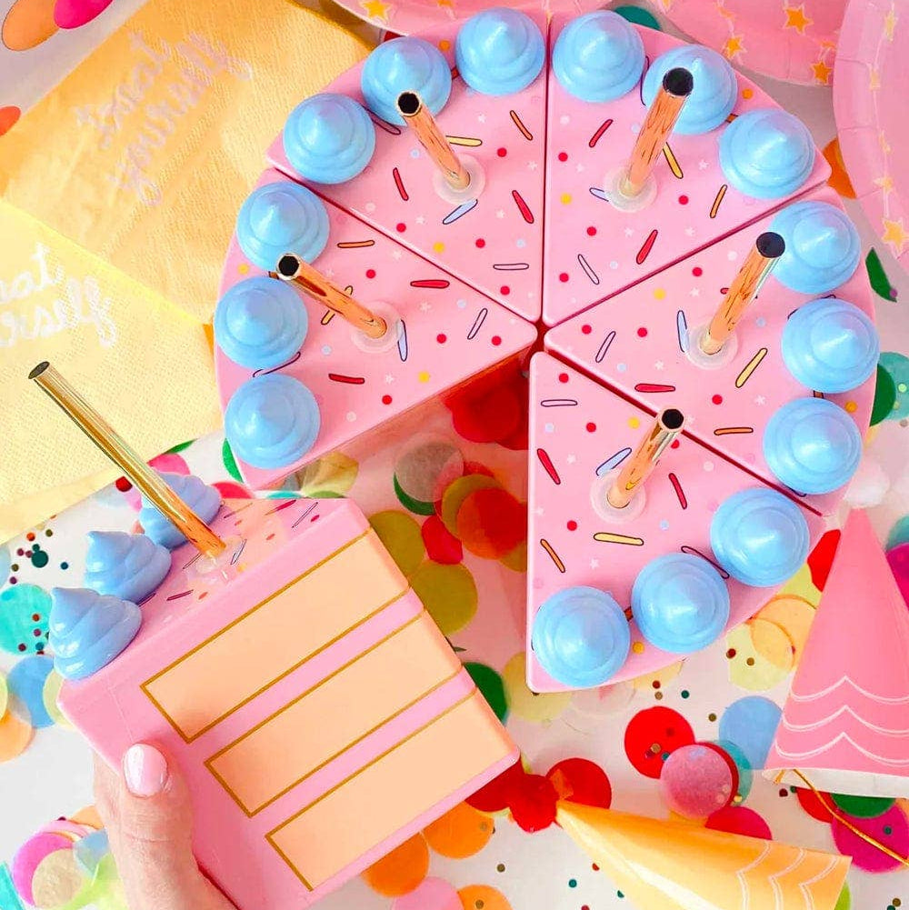 Pink birthday cake-shaped sipper with blue decorations on a colorful background.