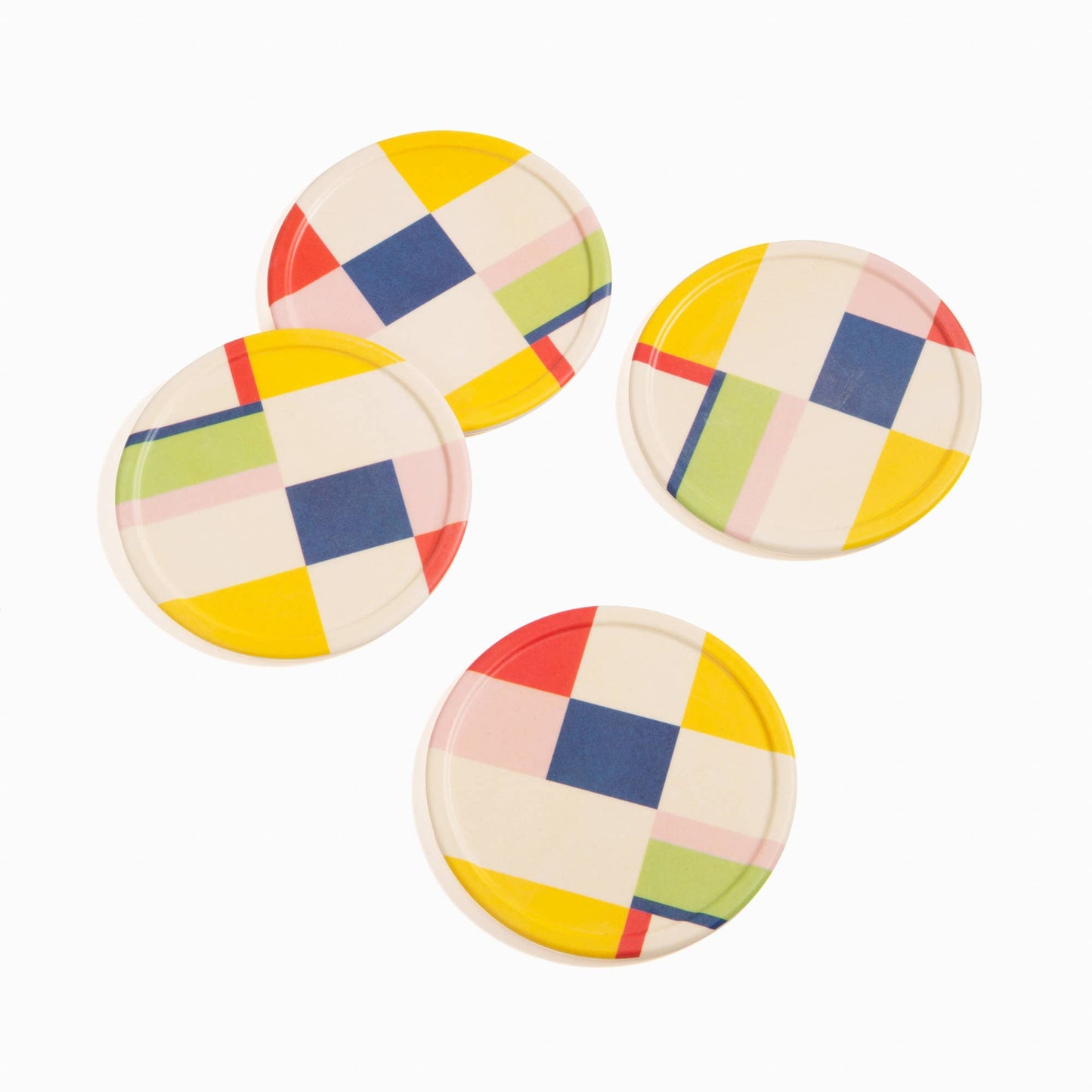 Four round, colorful checkered coasters on a white background