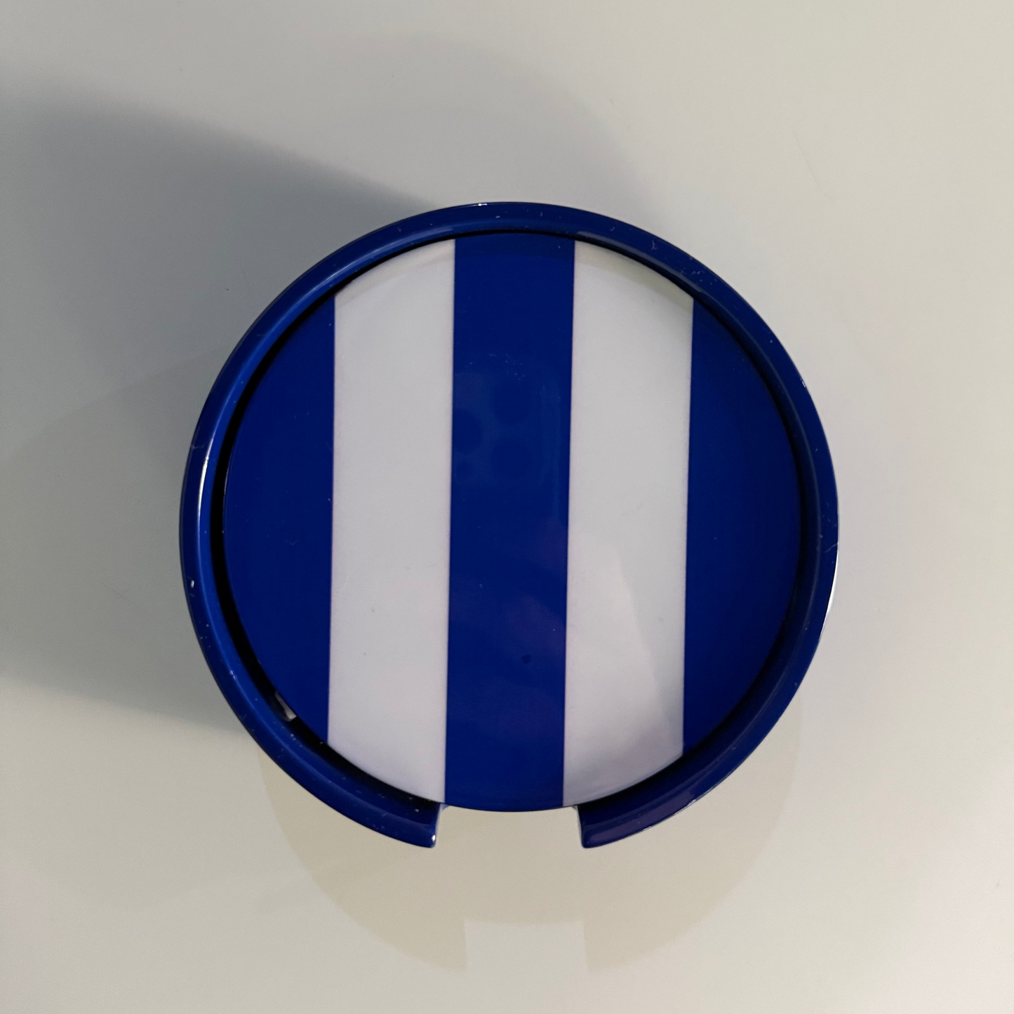A circular blue and white striped coasters, shown from a top-down view on a plain light background.