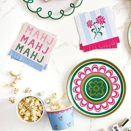 Colorful decorative plates with floral patterns, napkins, and a bowl of popcorn on a white surface.