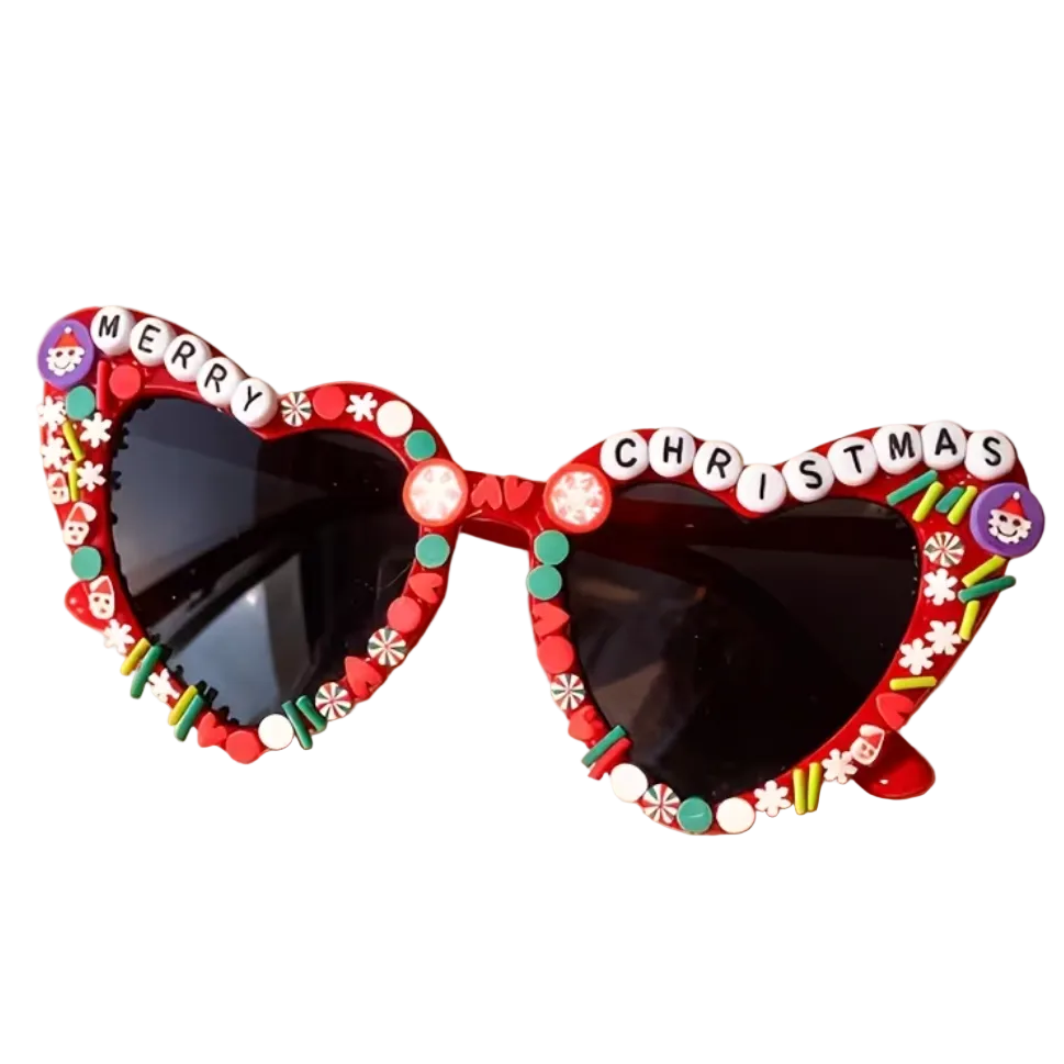 Christmas-themed heart sunglasses with dark lenses, decorated with red beads, white snowflakes, colorful candy-like embellishments, and letter tiles spelling 'MERRY CHRISTMAS' on the top frame, 