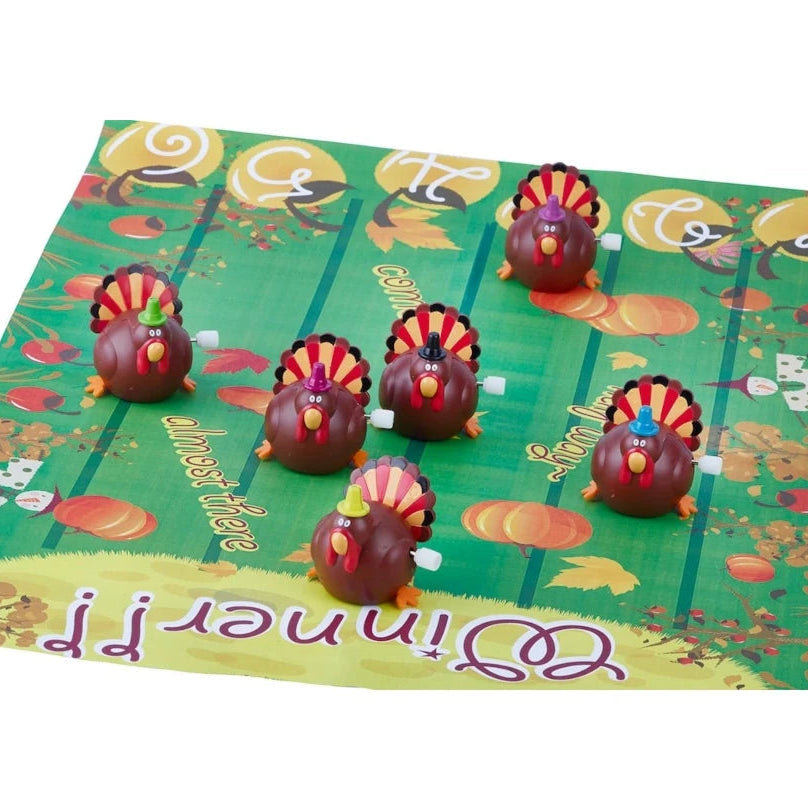 Turkey-themed board game with six small turkey figures arranged on a green printed game mat featuring autumn illustrations and the word 'Winner!' at the bottom.