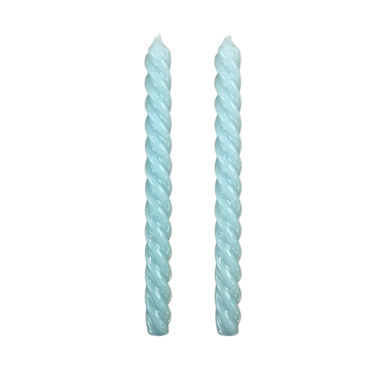 Two twisted taper candles in a pale icy blue color, standing upright on a plain white background.