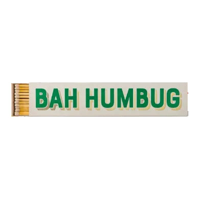 A rectangular matchbox with a row of lit wooden matches on the left and large green text reading 'BAH HUMBUG' on a white background.