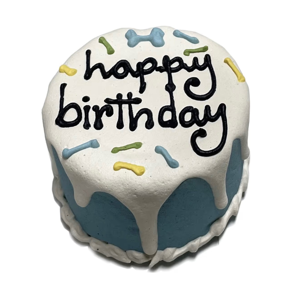 Small round cake for dogs with 'happy birthday' text and colorful bone sprinkles on a white background