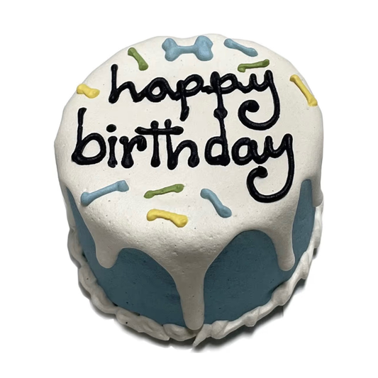 Small round cake for dogs with 'happy birthday' text and colorful bone sprinkles on a white background