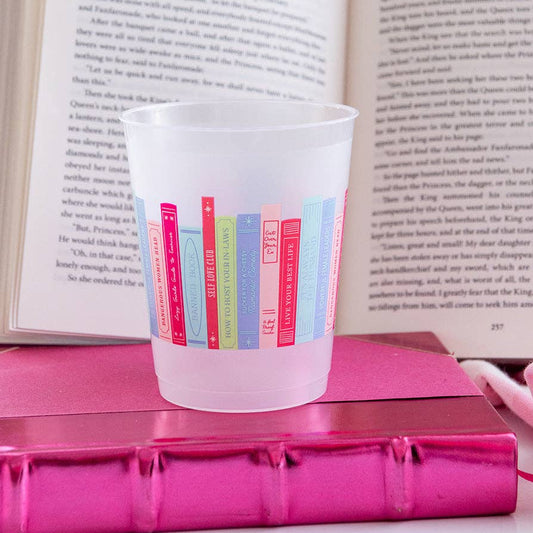 Frosted plastic cup with colorful book design on a pink book with an open book in the background.