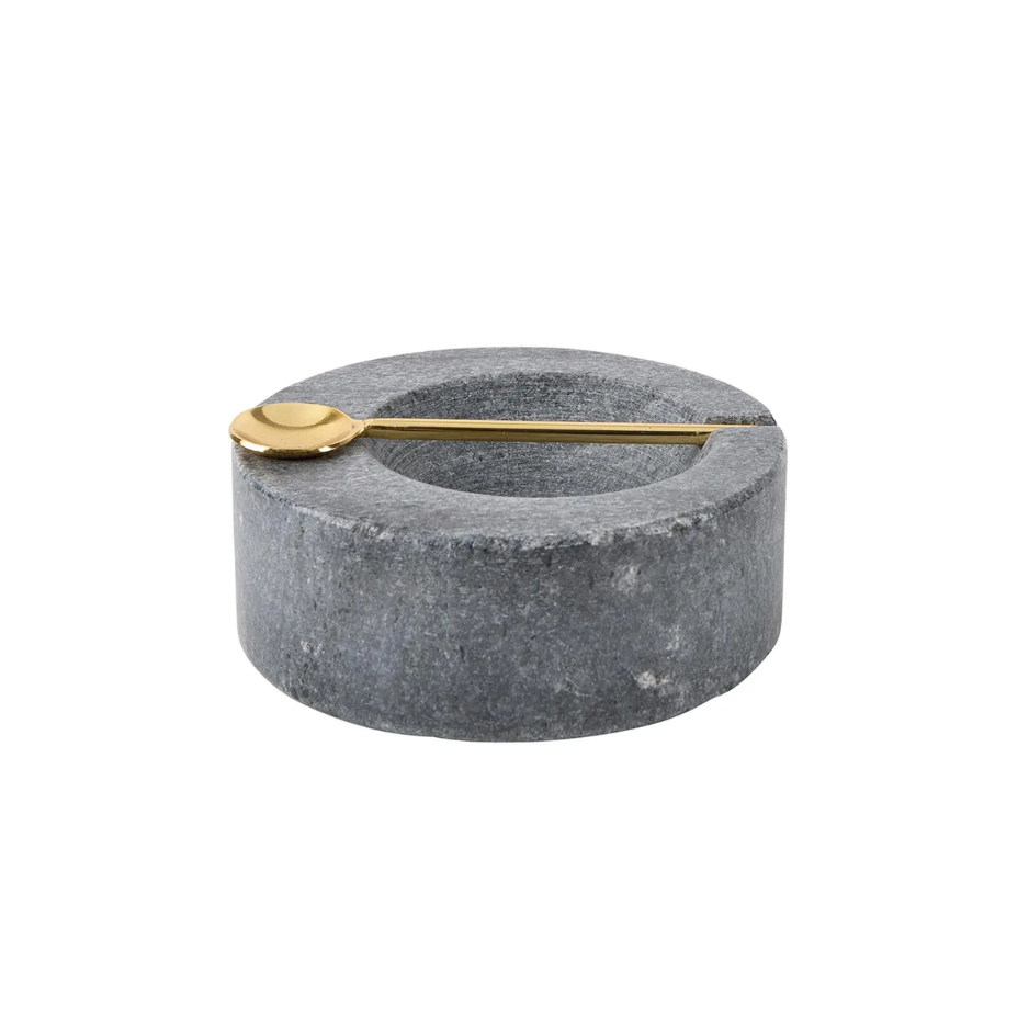 Gray stone bowl with a gold spoon on a white background
