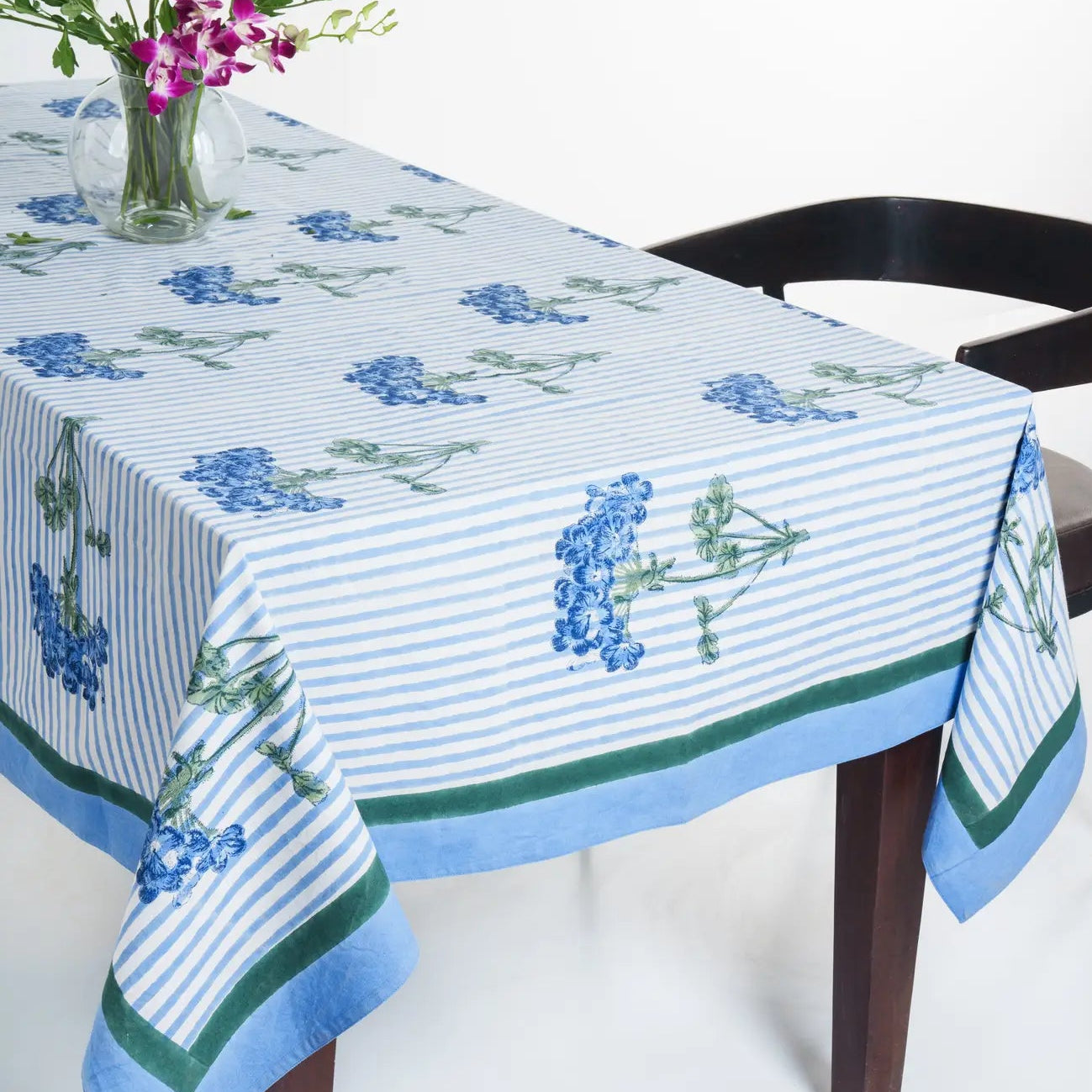 Tablecloth with floral design on a table with a vase of flowers.
