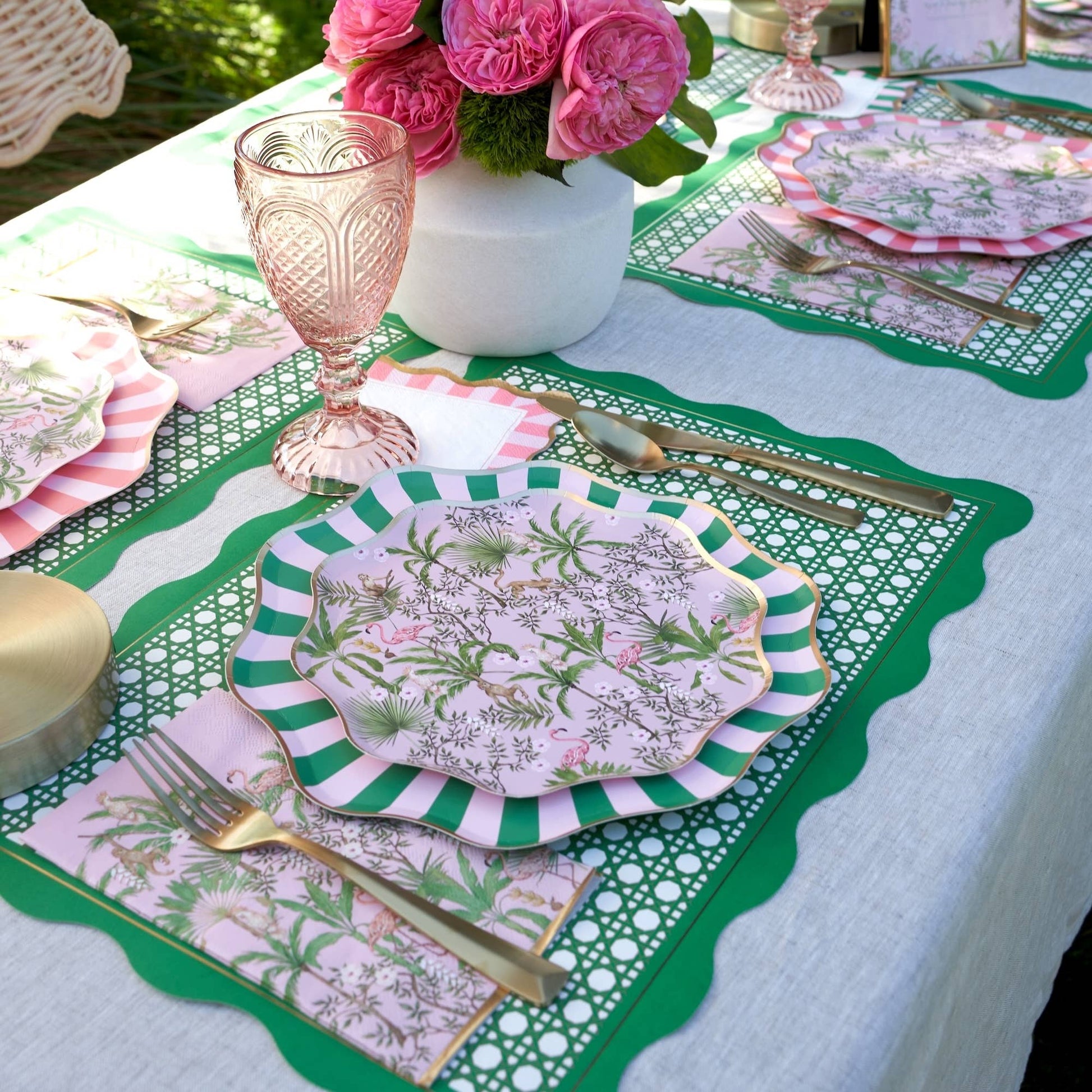 Decorative table setting with floral plates, pink glasses, and green placemats.