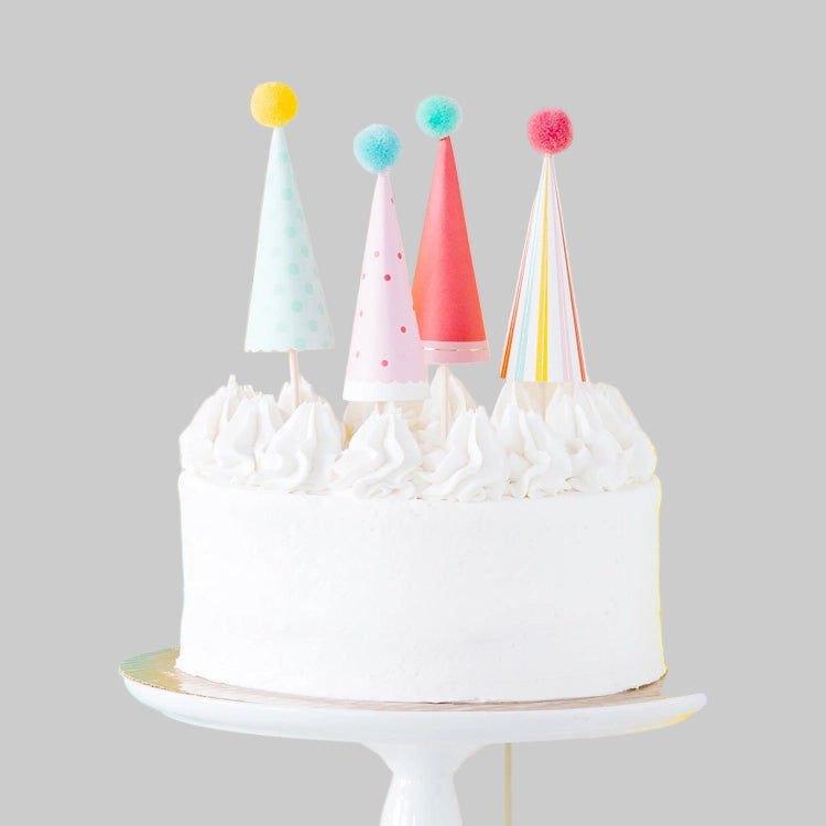 White cake with colorful party hats on a gray background
