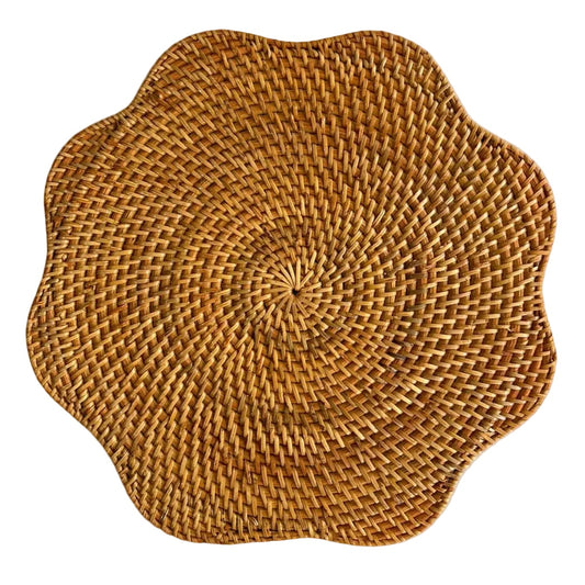 A round woven placemat with a scalloped edge, crafted from natural tan and brown raffia or wicker material, shown on a solid white background.