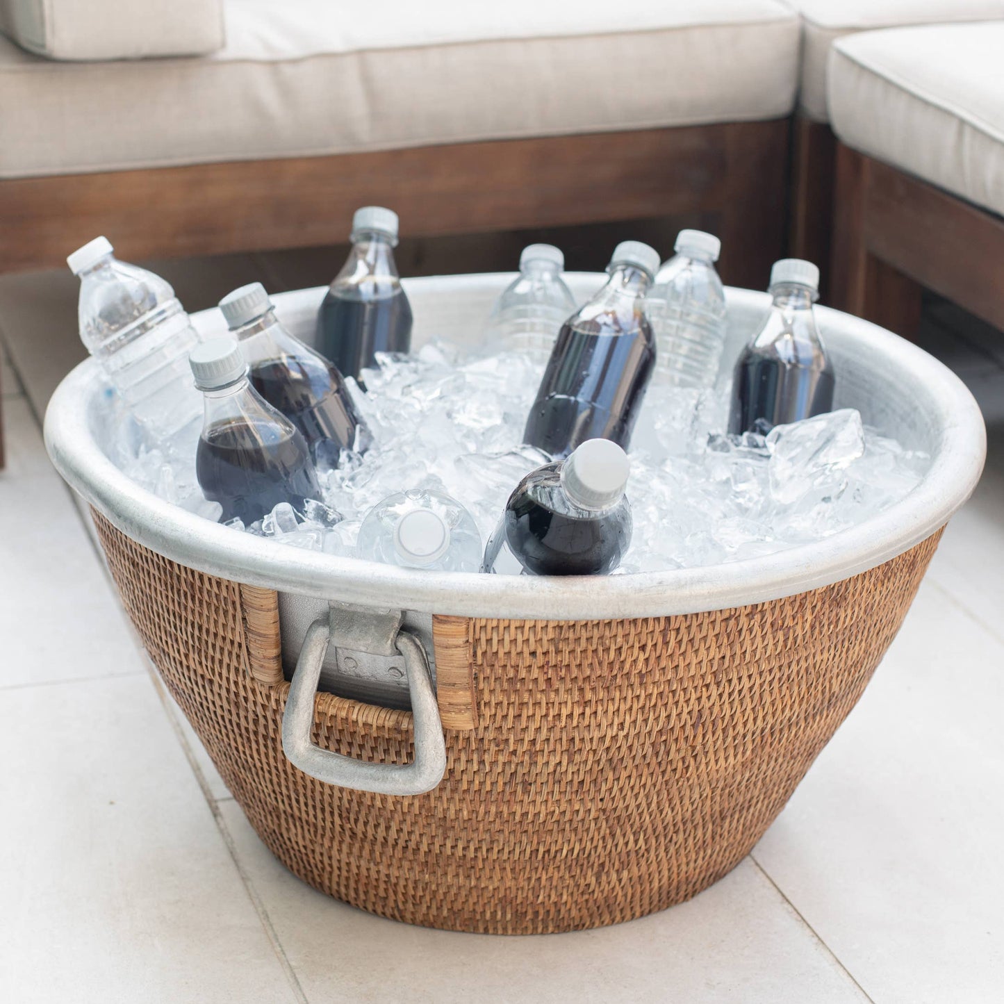 Wicker cooler with ice and bottles on a patio