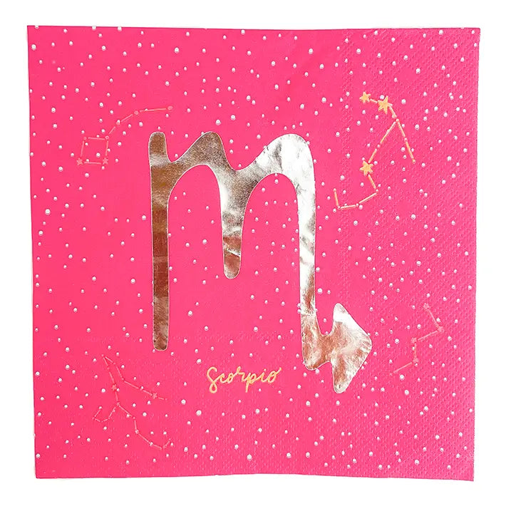 A square pink napkin featuring the zodiac sign 'Scorpio' in metallic rose gold foil, decorated with small white polka dots and gold constellation line drawings.