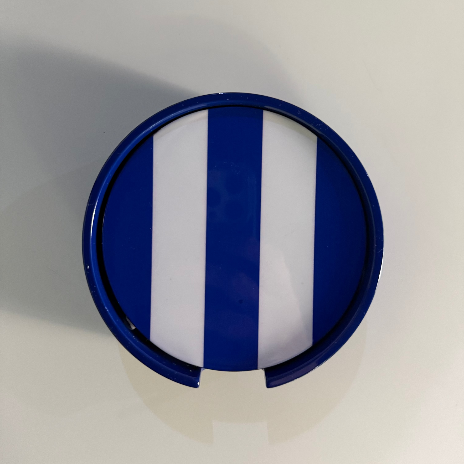 A circular blue and white striped coasters,  shown from a top-down view on a plain light background.