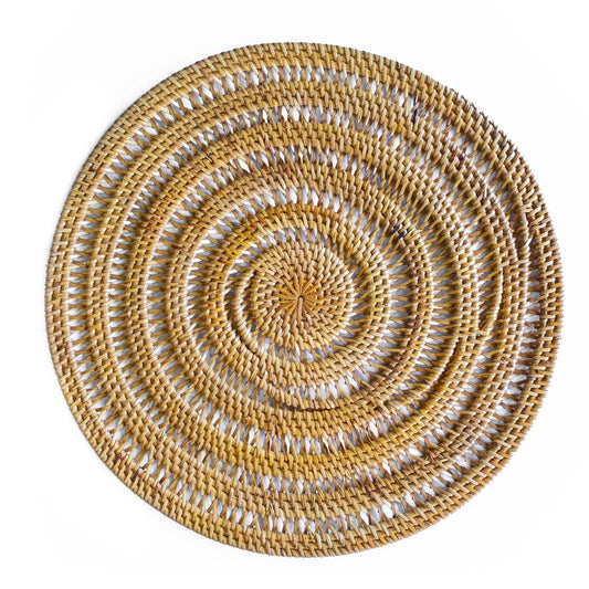 A round woven placemat with a spiral pattern, made from natural tan and light brown raffia or straw, photographed from directly above on a solid white background.